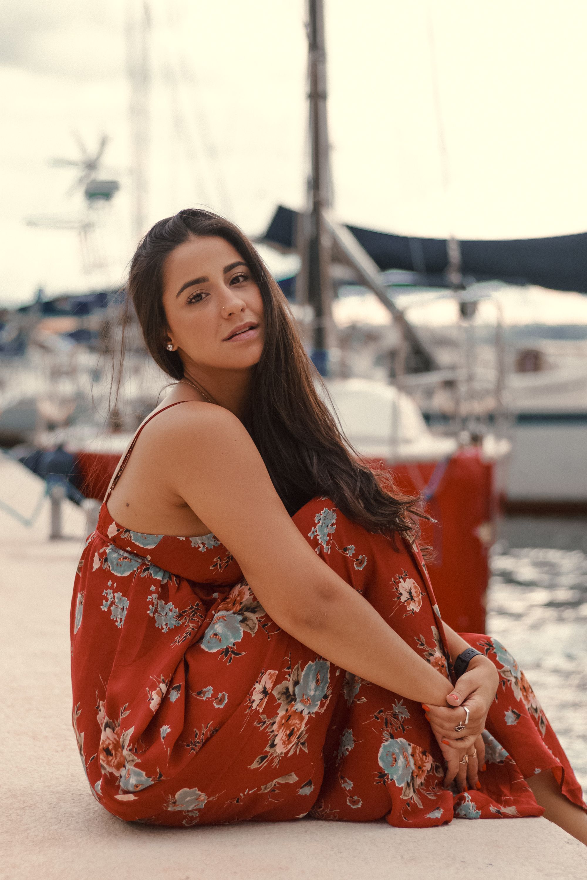 A woman in a floral dress sits by the marina in Brasília, exuding calm and elegance.