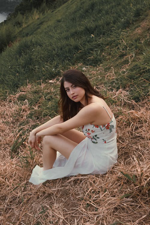 Free Woman in White Floral Dress Sitting on Grass Field Stock Photo