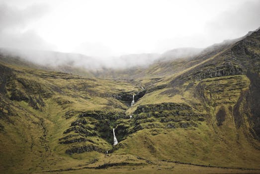 冰岛宁静的风景中，雾气笼罩的山脉和瀑布般的流水相映成趣