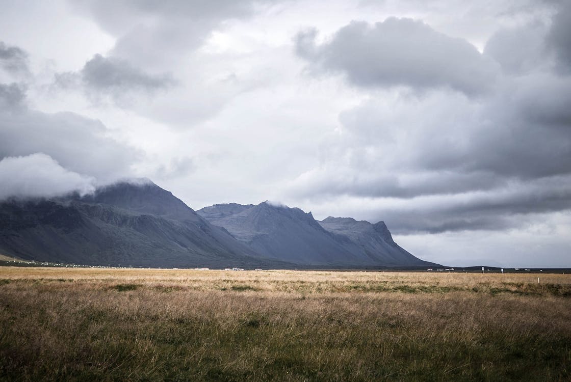 Campo Di Erba Marrone E Montagne Grigie Sotto Nuvole Grigie