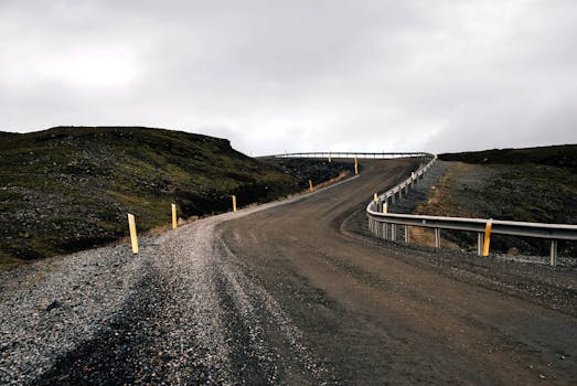 在乌云密布的天空下，一条蜿蜒的砾石路穿过崎岖的乡村，缓缓向上坡延伸