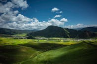 Green Grass Field and Mountain Under Blue Sky