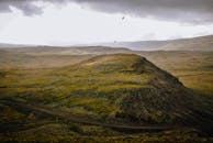 乌云下，岩石小山上飞鸟翱翔，展现自由与广阔