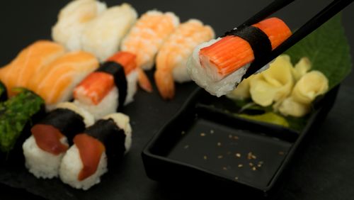 Free Vibrant sushi pieces with chopsticks highlighting fresh seafood on a black plate. Stock Photo
