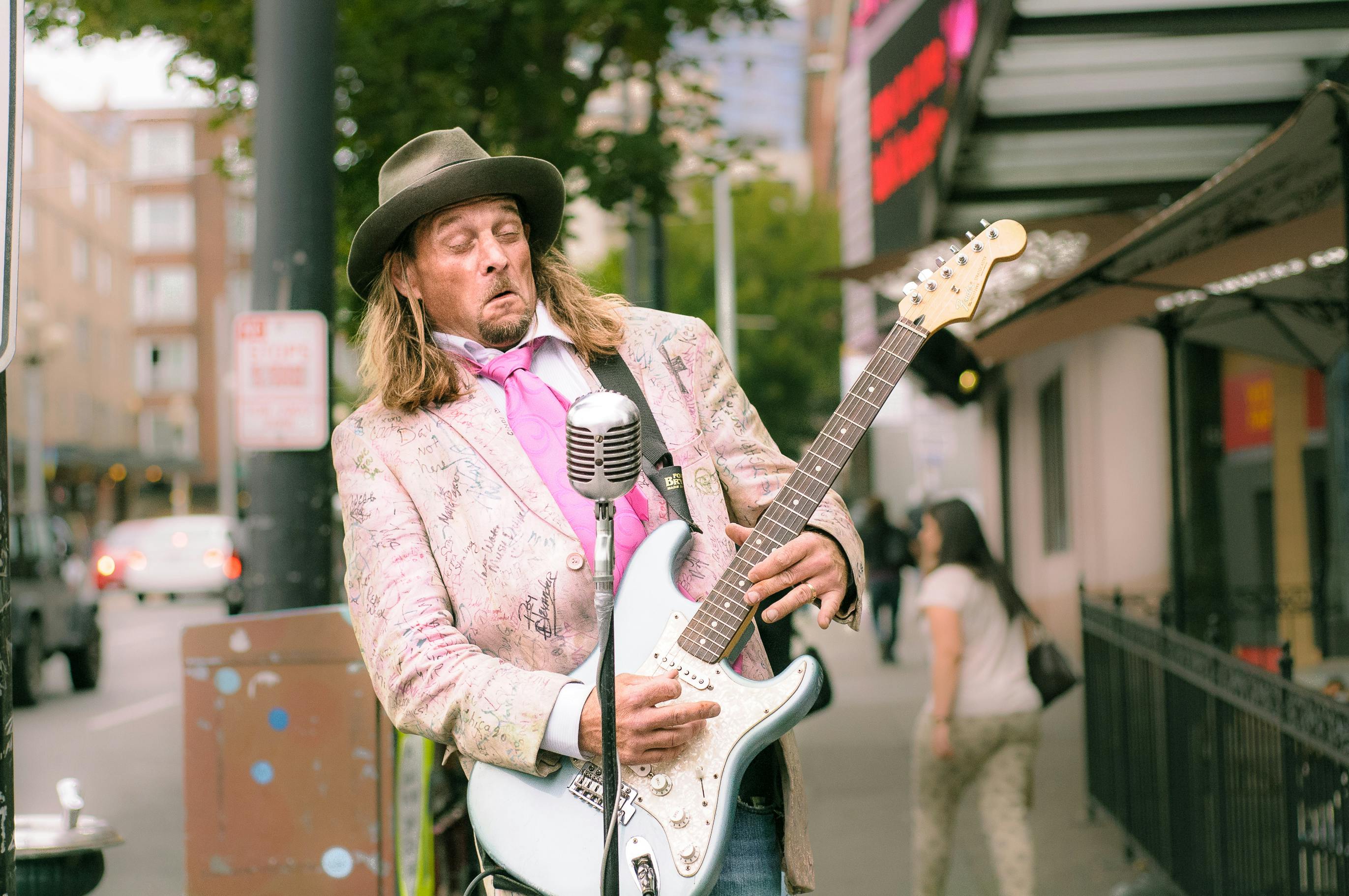 Musician performing with electric guitar and microphone on city street.