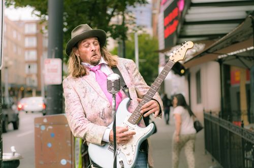 Free Musician performing with electric guitar and microphone on city street. Stock Photo