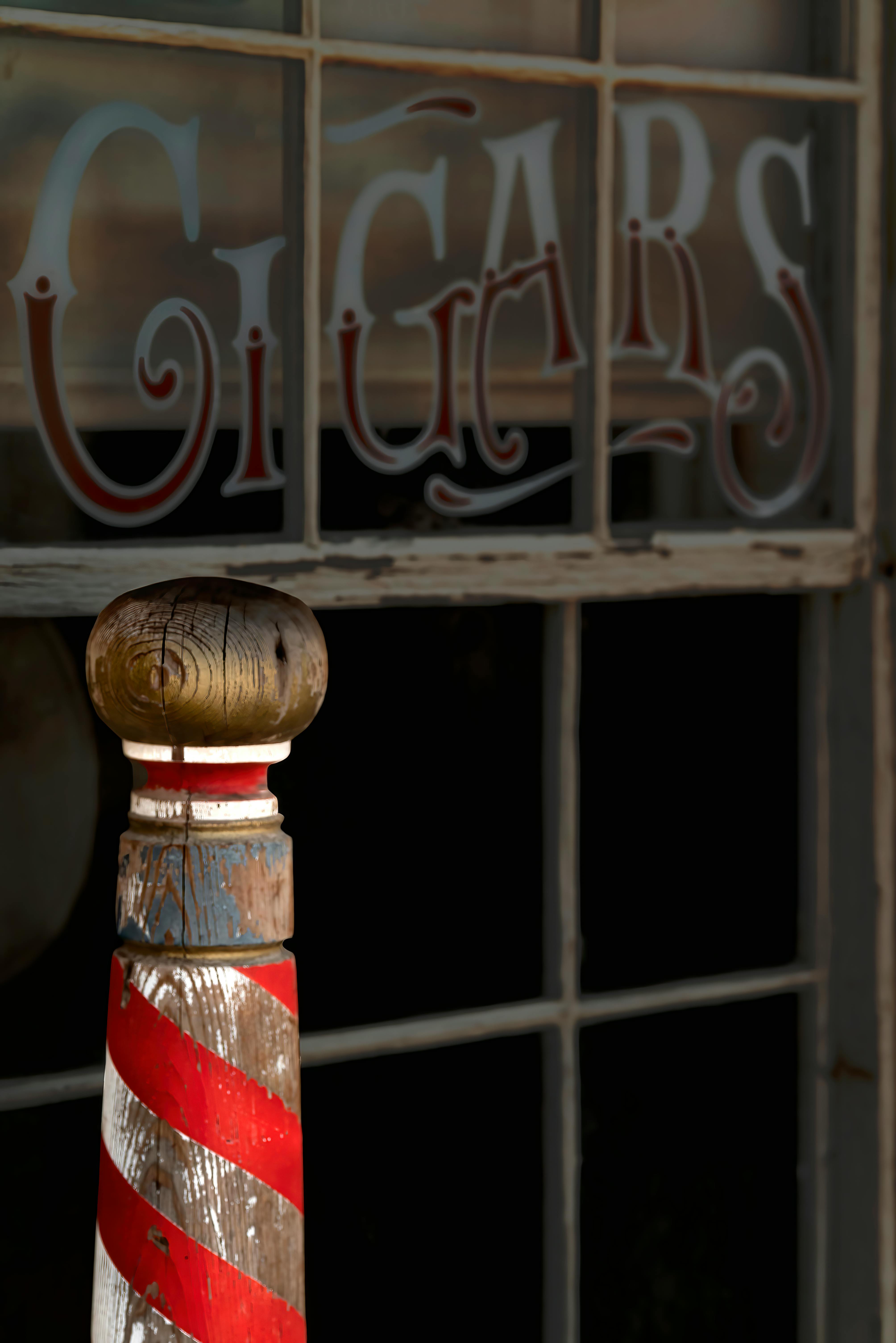 Close-up of a vintage cigars shop window and red striped barber pole in Randsburg, CA.