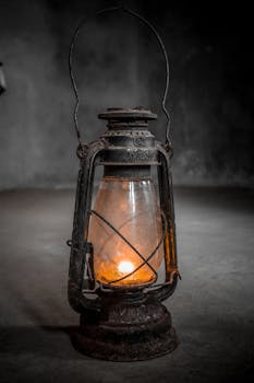 An antique lantern illuminated by a candle in a dim room, showcasing vintage charm.