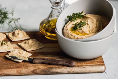 Free A beautifully styled hummus dish with crackers and olive oil, perfect for vegetarian cuisine lovers. Stock Photo