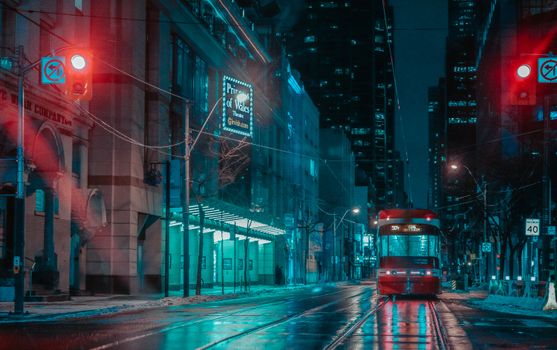 Moody nighttime view of a streetcar on a rainy street in downtown Toronto, Canada.