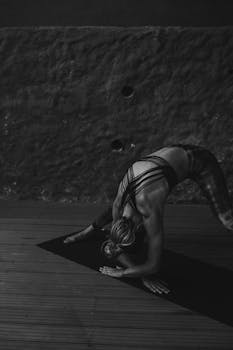 A woman practicing yoga in grayscale, showcasing strength and flexibility.