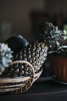 A close-up of a pineapple in a wicker basket with a moody and dark tone.