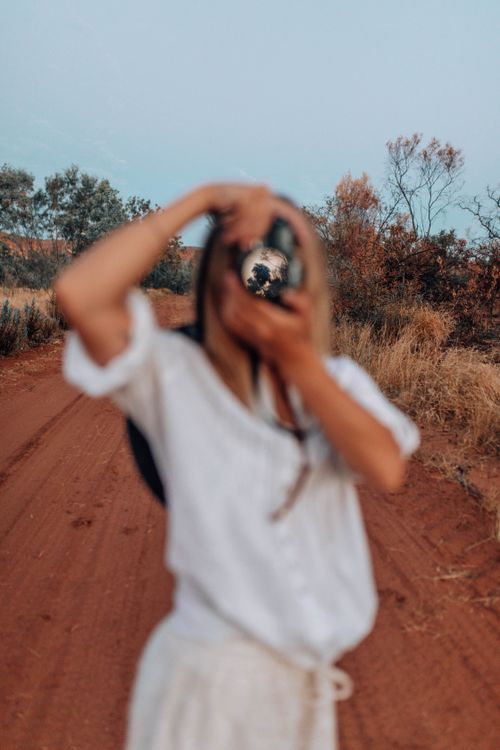 Free Blurred woman photographing a rural scene on a red dirt road. Outdoors in summer. Stock Photo
