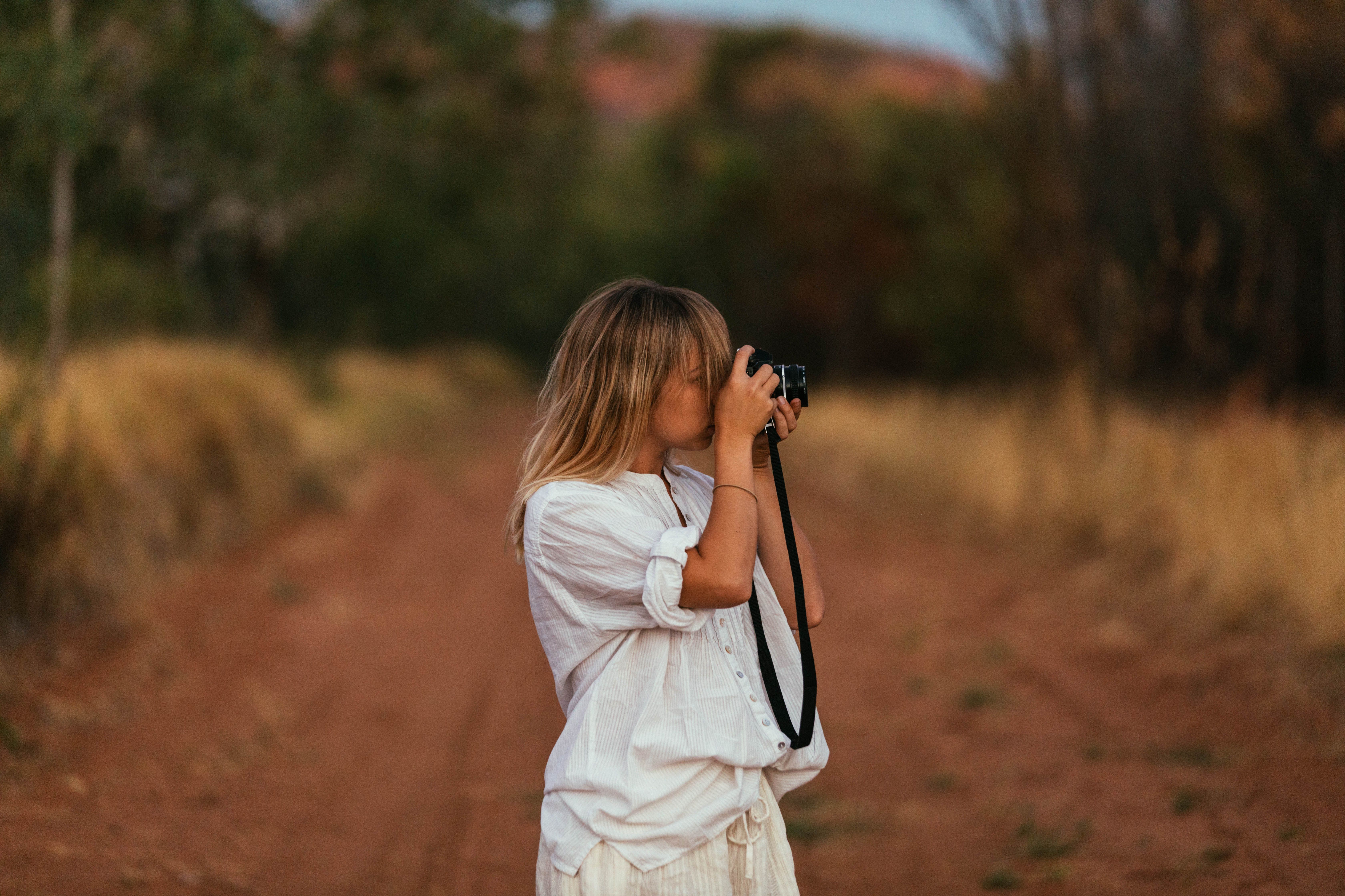 A young woman captures nature with her camera on a scenic trail.