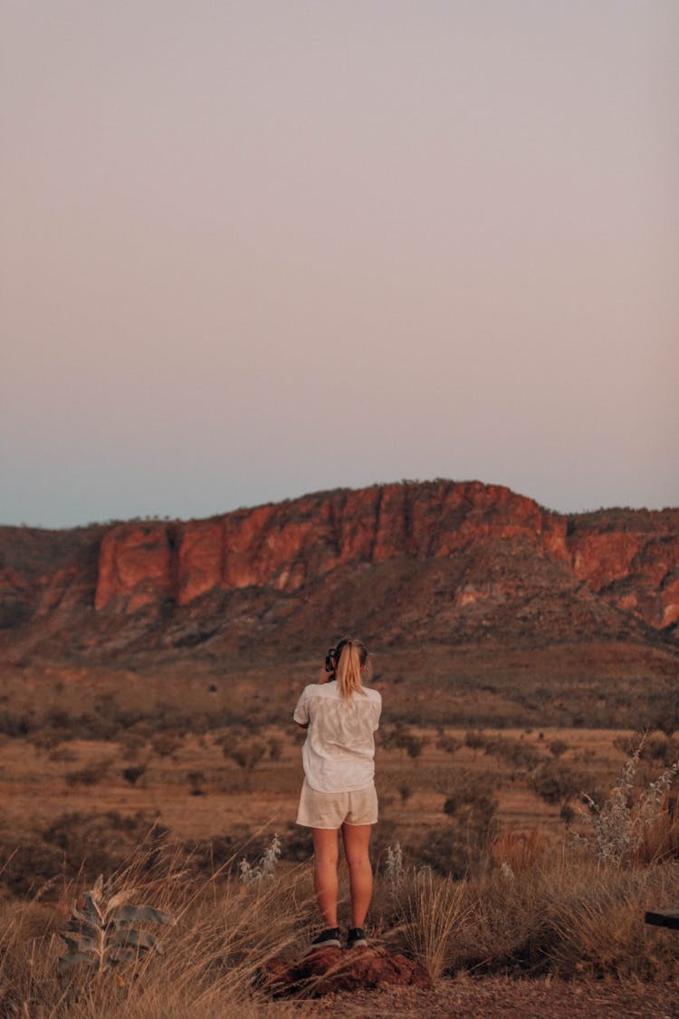 Woman Standing On Plains With View On Rocks