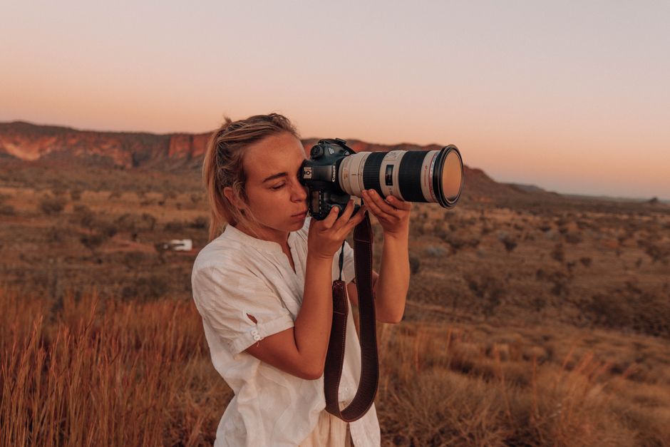female photographer holding camera in desert landscape at sunset