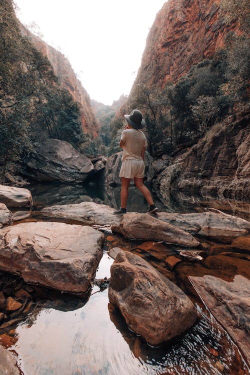 Free Woman Standing on Rocks in the Middle of a River Down the Canyon  Stock Photo