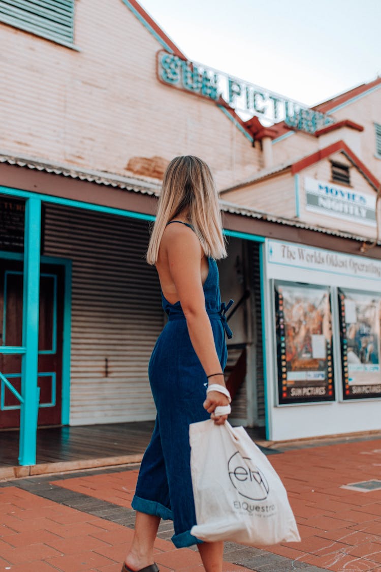 Woman Holding A Shopping Bag And Standing Outside Of A Movie Theatre