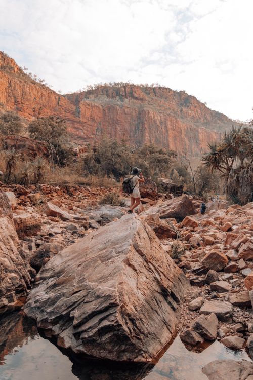 Free Woman hiking through a rugged canyon landscape with striking rock formations. Stock Photo