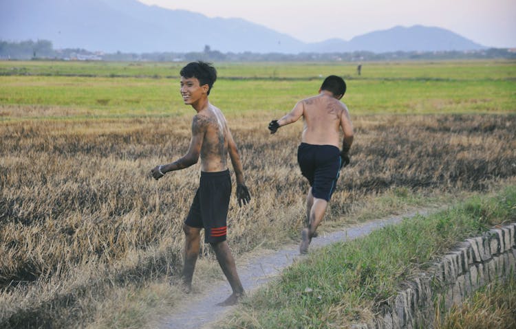 Two Boys Running On A Grassy Field