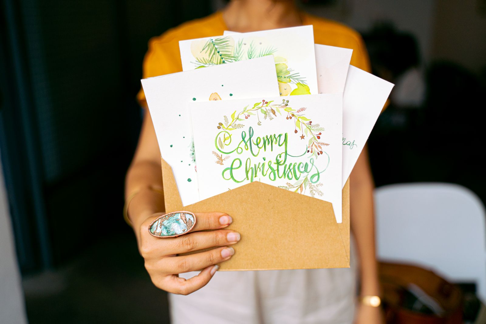 Hands holding printed Christmas cards and an envelope.