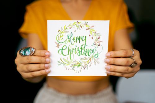 Free Bright and festive Christmas card held by hands against a blurred background. Stock Photo