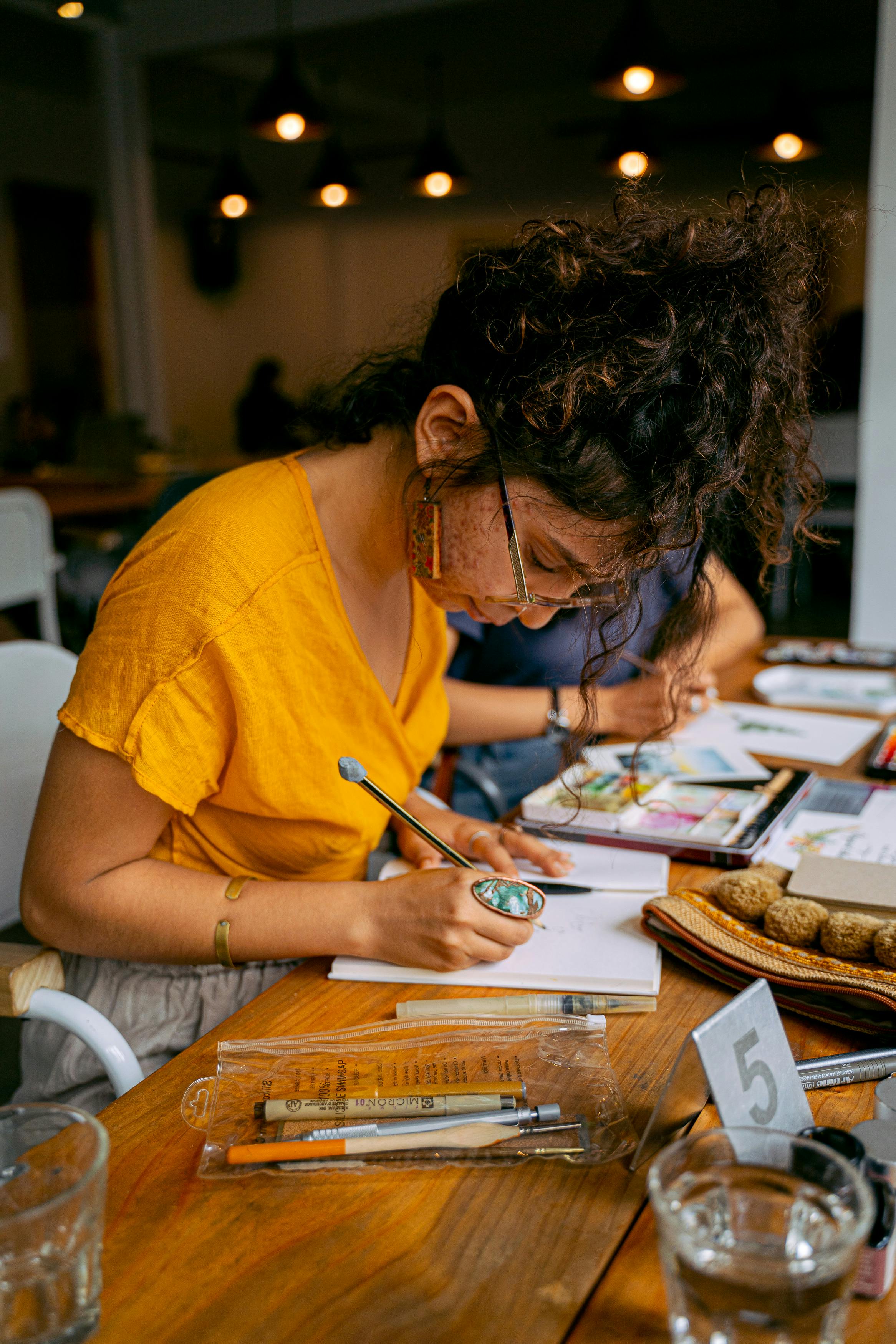 woman in yellow t shirt writing on white paper