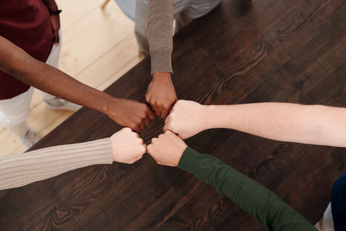 Equipo uniendo las manos en señal de colaboración, vista superior