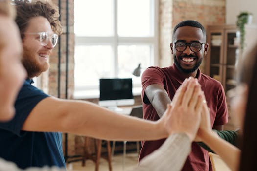 Happy diverse colleagues joining hands in a teamwork celebration at an office.