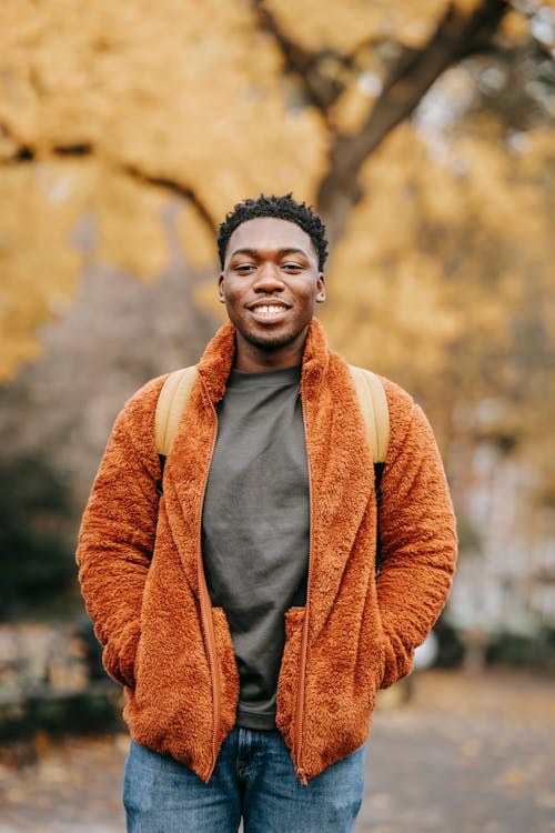 Smiling young black guy looking at camera in autumn park