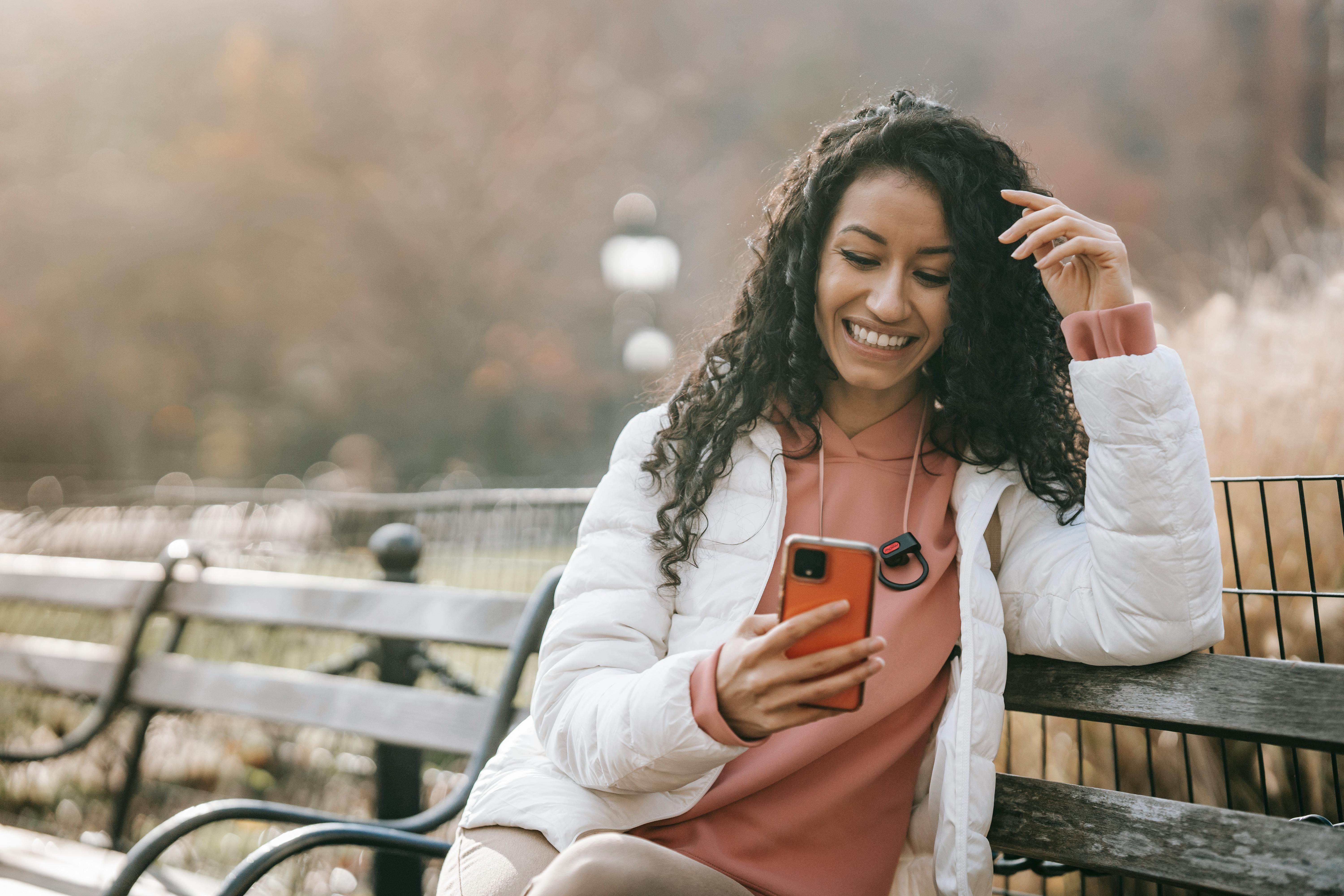 cheerful latin american woman with smartphone