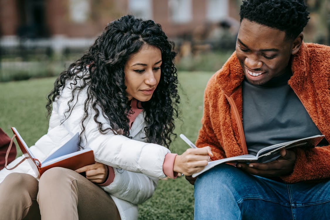 Free Cheerful multiethnic students studying together in campus park Stock Photo