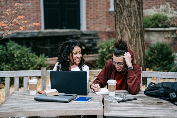 Diverse Students Working Together At Table With Laptop In Park