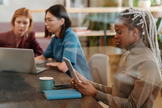 Three professional women working together with technology in a modern office setting.