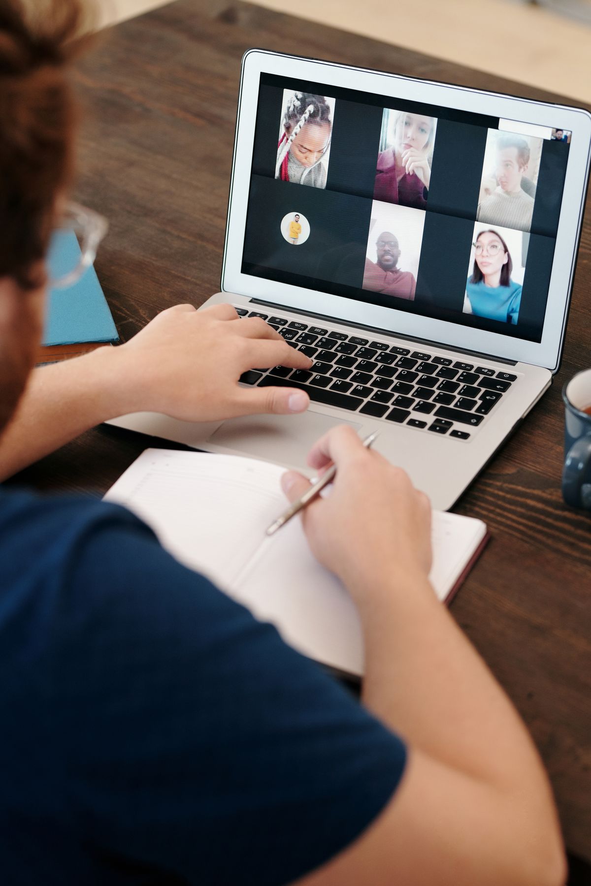 Professional taking notes during a virtual meeting on a laptop
