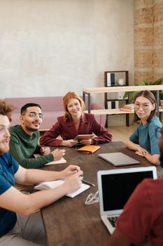 Engaged team of young adults collaborating in a modern office setting, promoting teamwork and idea sharing.