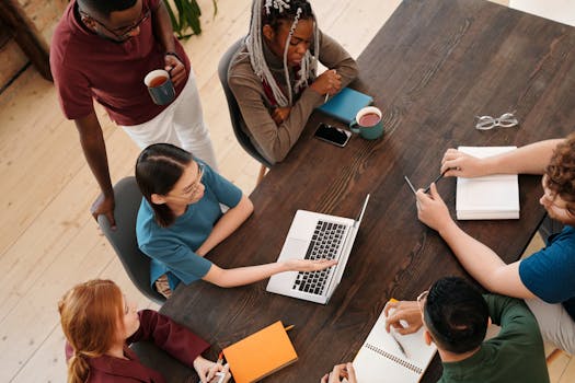 Top view of a diverse team collaborating in a meeting with laptops and notes.