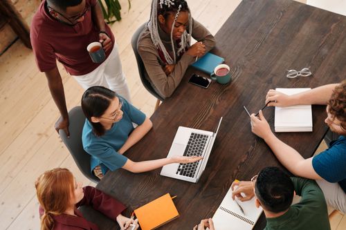 Free Top view of a diverse team collaborating in a meeting with laptops and notes. Stock Photo