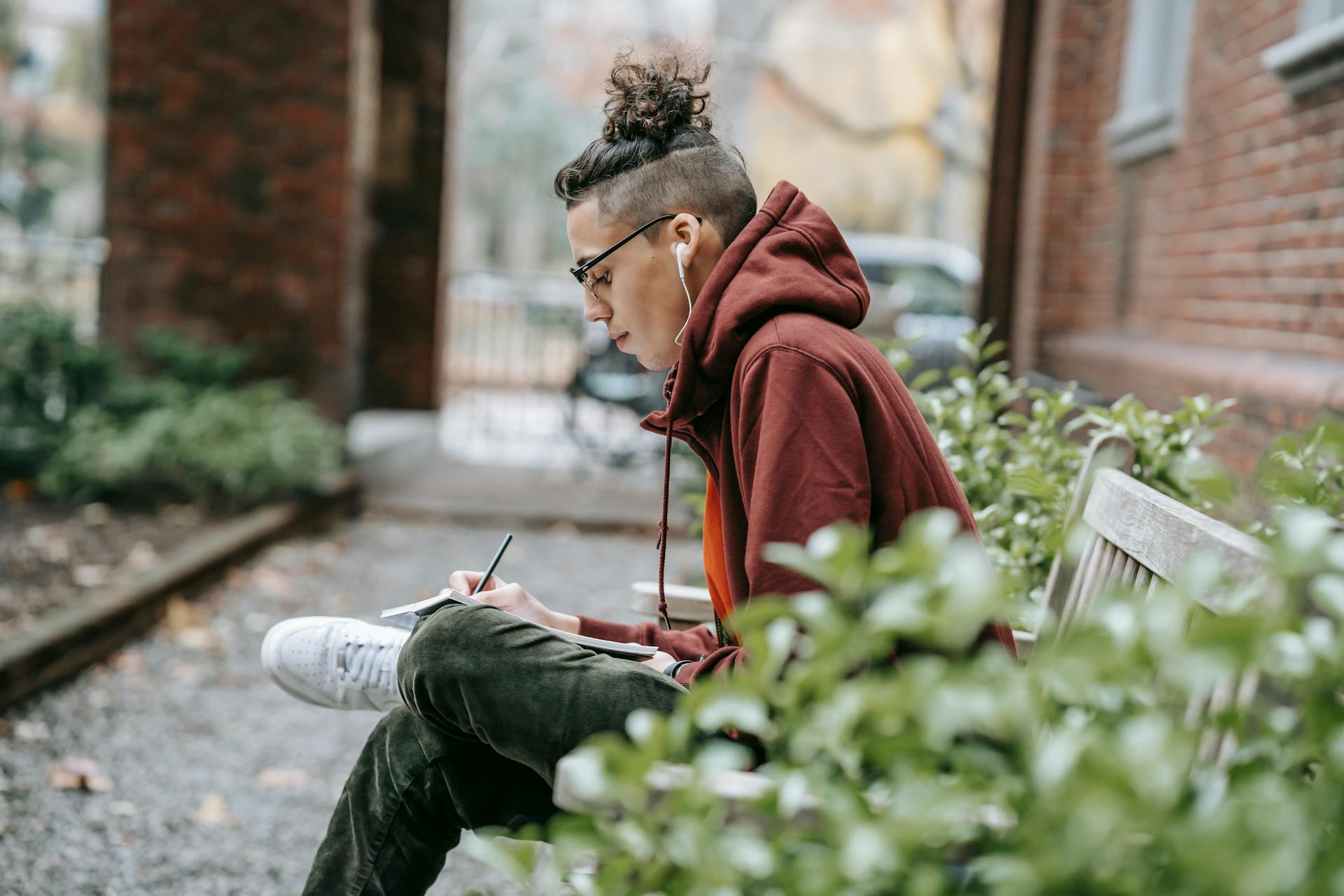 Young intelligent man with trendy hairstyle writing on paper