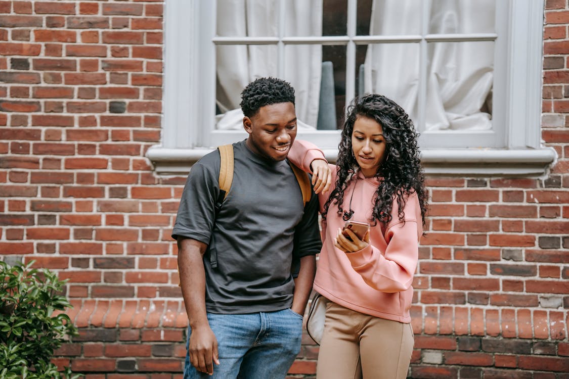 Diverse young happy students using smartphone