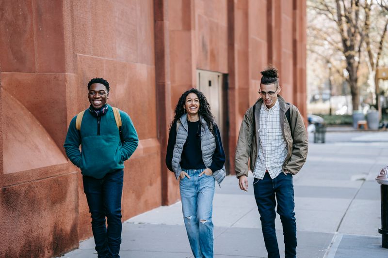 Three young friends enjoying a cheerful walk outside on a sunny day, showcasing friendship and leisure.