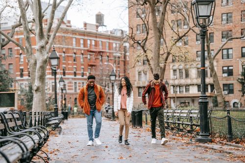 Free Full length of young positive multiracial friends in casual clothes walking in city park after studies on autumn day Stock Photo