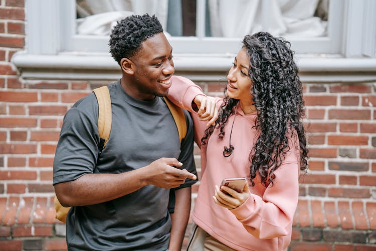 Happy Young Diverse Couple Sharing Smartphone On Street