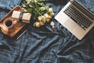 家庭办公室布置舒适，配有笔记本电脑、玫瑰、咖啡以及蓝色面料上的配件