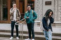 Diverse male teens scoffing at ethnic female walking on street