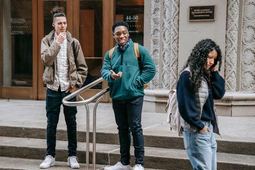 Diverse male teens scoffing at ethnic female walking on street