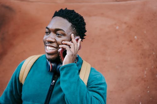 Joyful young black guy talking on smartphone on street