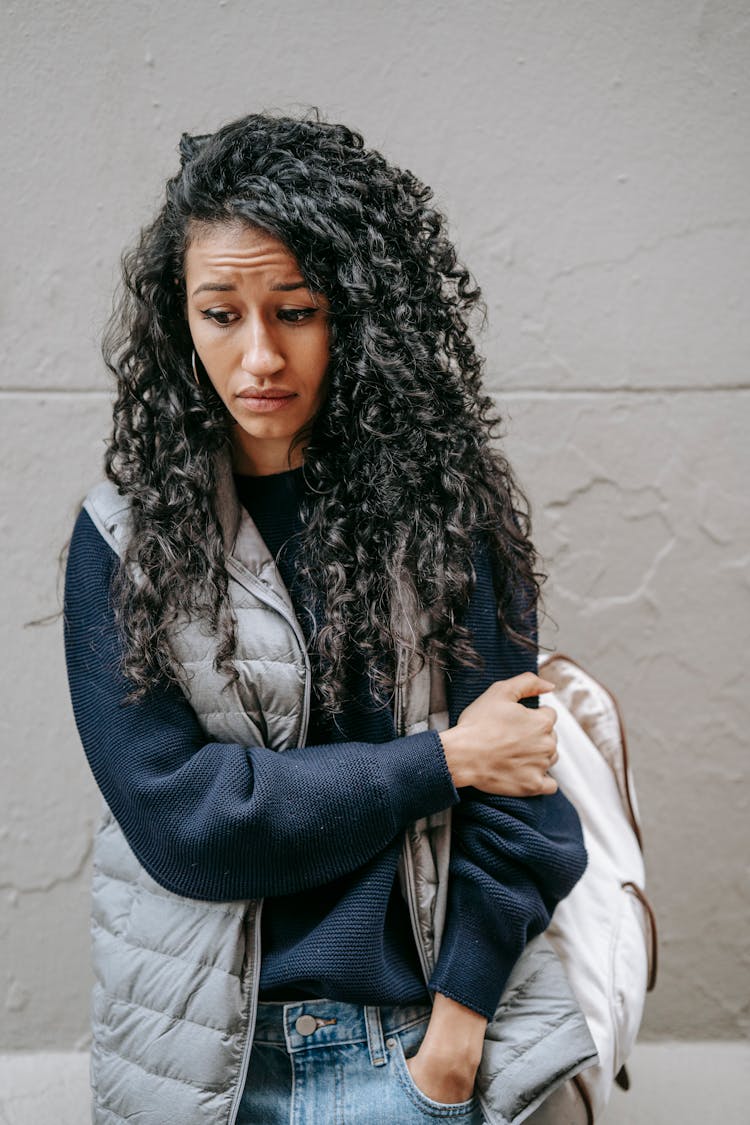 Sad Young Ethnic Lady Standing On Street And Looking Down