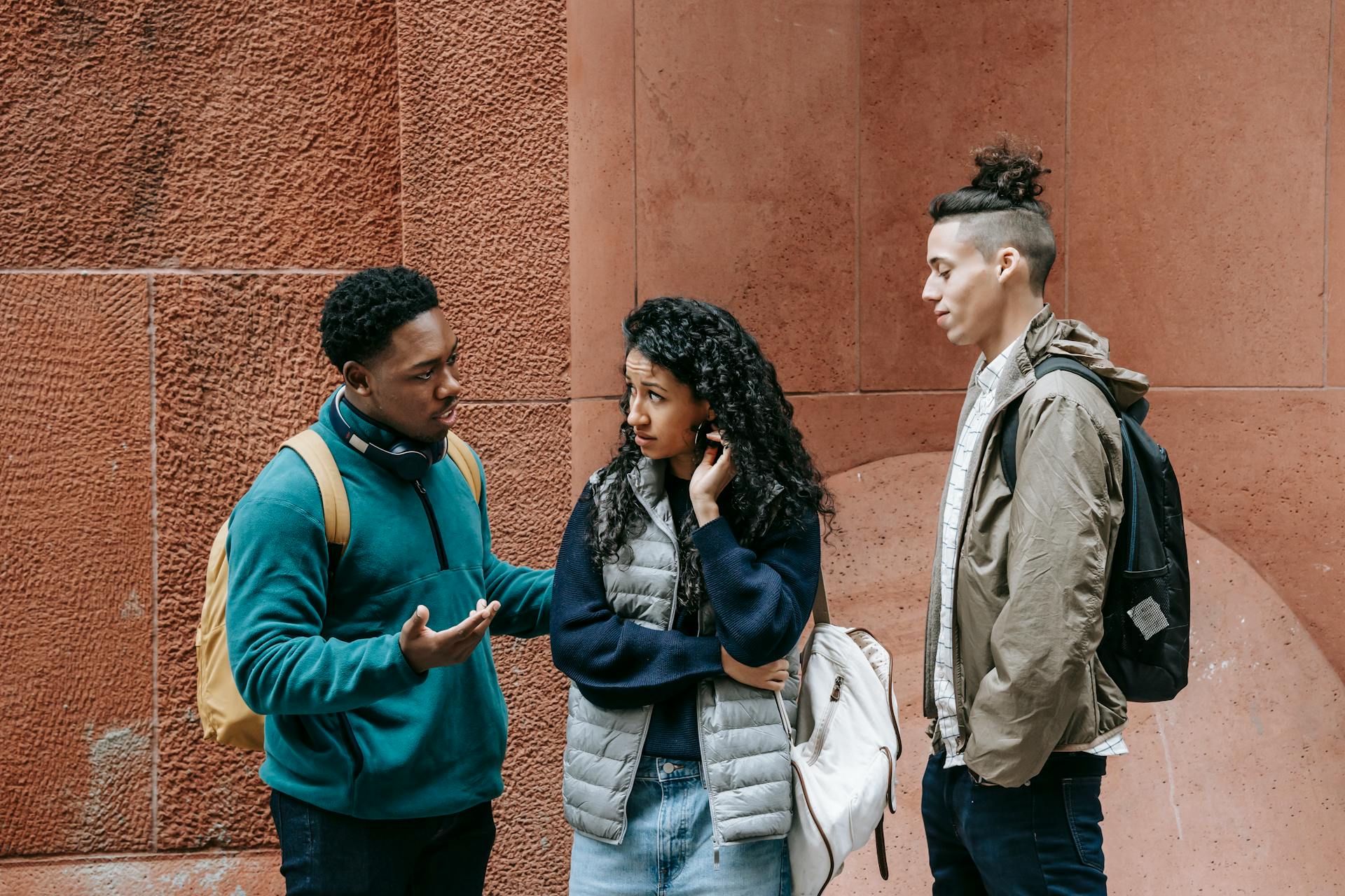 Three diverse students engage in a thoughtful discussion outdoors, embodying modern campus life.