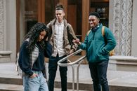 Happy young diverse guys gazing on ethnic female walking on street